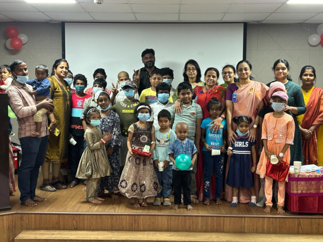 Children and adults on stage with gifts and balloons, some wearing masks.