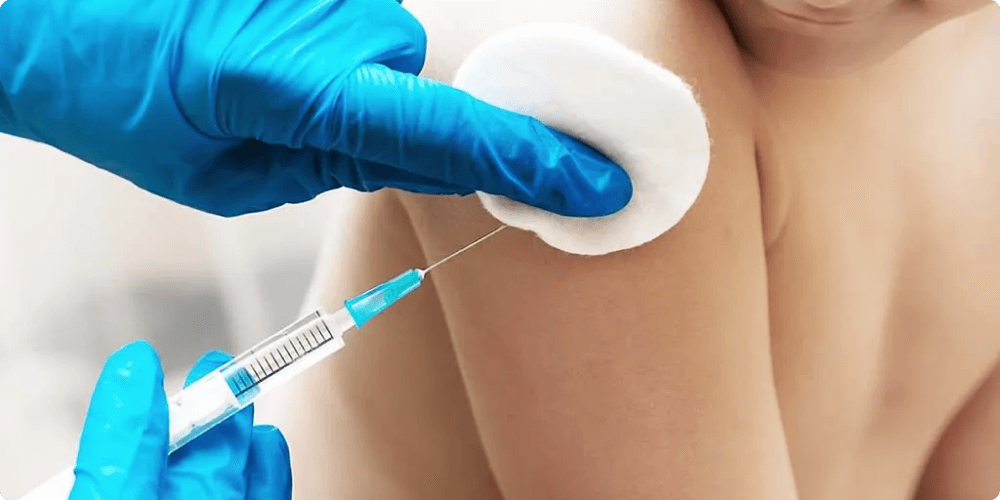 A gloved hand injects a child's arm, while the other holds a cotton swab.